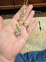 Necklace draped on hand showing gold chain and iridescent crystal drops