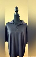 Front view of black polo shirt on mannequin