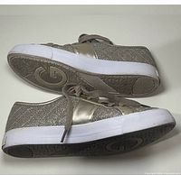 Side view of both sneakers showing metallic gold glitter uppers and white soles