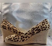 Side profile of both shoes showing leopard canvas and jute wedge heels