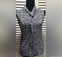 Front view of navy and white Michael Kors sleeveless tie-neck blouse on mannequin