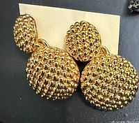 Close-up of gold-tone granulated double-disc earrings