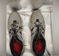 Top view showing pair of gray mesh New Balance shoes, laces tied, red insoles visible