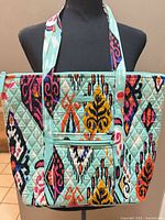 Front view of tote showing overall shape, pattern, handles and exterior zip pocket