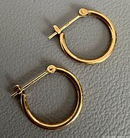 Pair of yellow gold hoop earrings on grey background