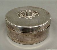 Closed round silver-plated box showing exterior and side wear