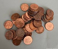 Pile of assorted Canadian 1-cent coins with one copper 5-cent coin
