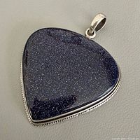 Front view of triangular blue sandstone pendant in silver setting