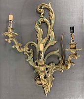 Front view of entire ornate bronze wall sconce showing three light arms and patina