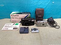 All items included: Fujifilm DL-270 camera with box and manual, Canon SD550 with charger, power cable, pouch, mini digital camera