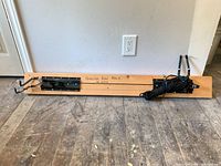 Full view of bike rack showing wood base, metal brackets, hooks, pulley and coiled rope