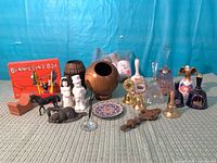 Group shot of entire lot showing bells, shakers, wood vases, figurines, plate, postcards bag, box toy