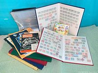 Lot overview showing open stamp albums, binder pages, Philatopic Magazine and Disneyland booklet