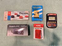 All five boxed items laid out: Sunny radio, Armitron receiver, Travelers' radio, Yahtzee handheld game, American Checkers set