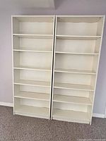 Front view of two white MDF bookshelves showing full height and shelves