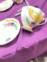 Teacup and saucer showing eagle motif and flags