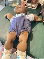 Full back view of doll showing cloth body, denim overalls and sneakers