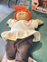 Full view of doll lying on table showing outfit and overall condition