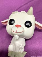 Front view of white vinyl goat figure showing facial details and seated pose