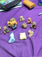 Group shot of all eleven teddy bear figurines on purple cloth