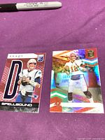 Both Tom Brady Panini Elite cards side-by-side on tabletop