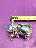 Side view of silver metal animal keychain with clasp and measuring tape showing under 3 inches