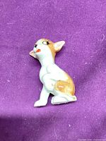 Front angled view of small porcelain puppy figurine showing coloration and seated pose