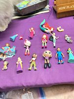 Overall group of approximately 17 assorted mini plastic figures on purple surface