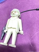 Full view of off-white figure with rifle and helmet cord visible