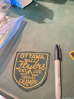 Front of Ottawa Flyers embroidered shield-shaped patch beside marker for scale