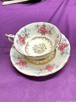 Teacup resting on saucer showing floral pattern and gold gilt detail