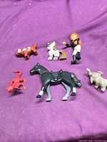 Group shot of all six plastic figures on purple background