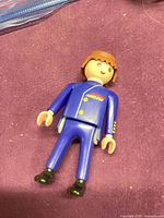 Front view of Playmobil figure showing blue suit, emblem, and black shoes