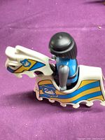 Side view of knight seated on white horse with striped barding