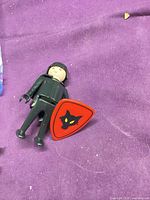 Full view of Playmobil knight figure and shield on purple background