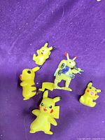 All five yellow plastic Pokemon figures on purple cloth