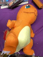 Full view of orange Charmander plush toy on purple surface