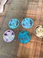 Five Pokémon collectible discs displayed on fabric surface