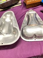 Two aluminum penis-shaped cake pans side by side