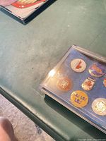 Overall view of six enamel pins in plastic display case