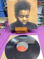 Front cover of Tracy Chapman LP on stand, record on table showing Elektra label