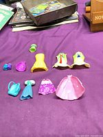 All 12 plastic doll clothing and accessory pieces displayed