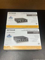 Front view of two sealed Netgear GS305 switch boxes