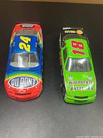 Top view of both 1:24 scale NASCAR cars showing #24 DuPont and #18 Interstate Batteries liveries