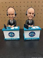 Front view of two Steve Martin talking bobbleheads at desks