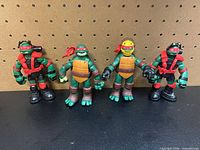 Front view of all four TMNT figures standing side by side