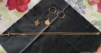 All jewelry pieces laid out: chain with cross, heart pendant, round charm, pair hoops