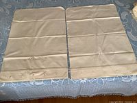 Pair of linen pillowcases laid flat showing embroidery and button hem