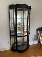 Full view of espresso curved glass curio cabinet against wall