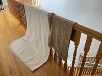 White chenille coverlet and beige fringed throw draped over railing